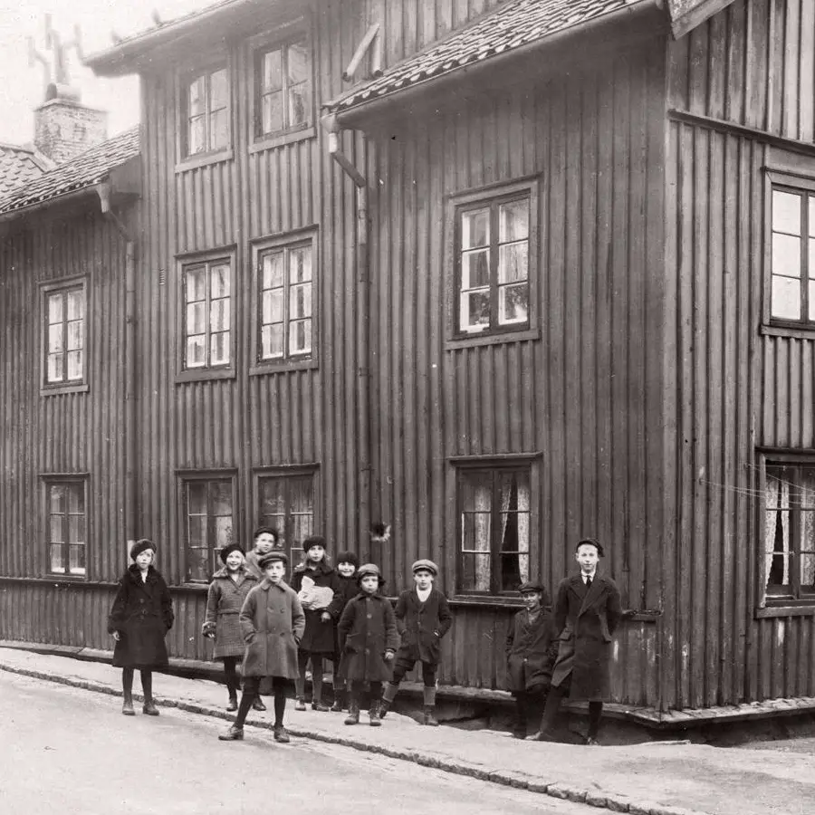 Svartvit historisk bild av barn framför ett trähus vid Skomakaregatan i Göteborg.