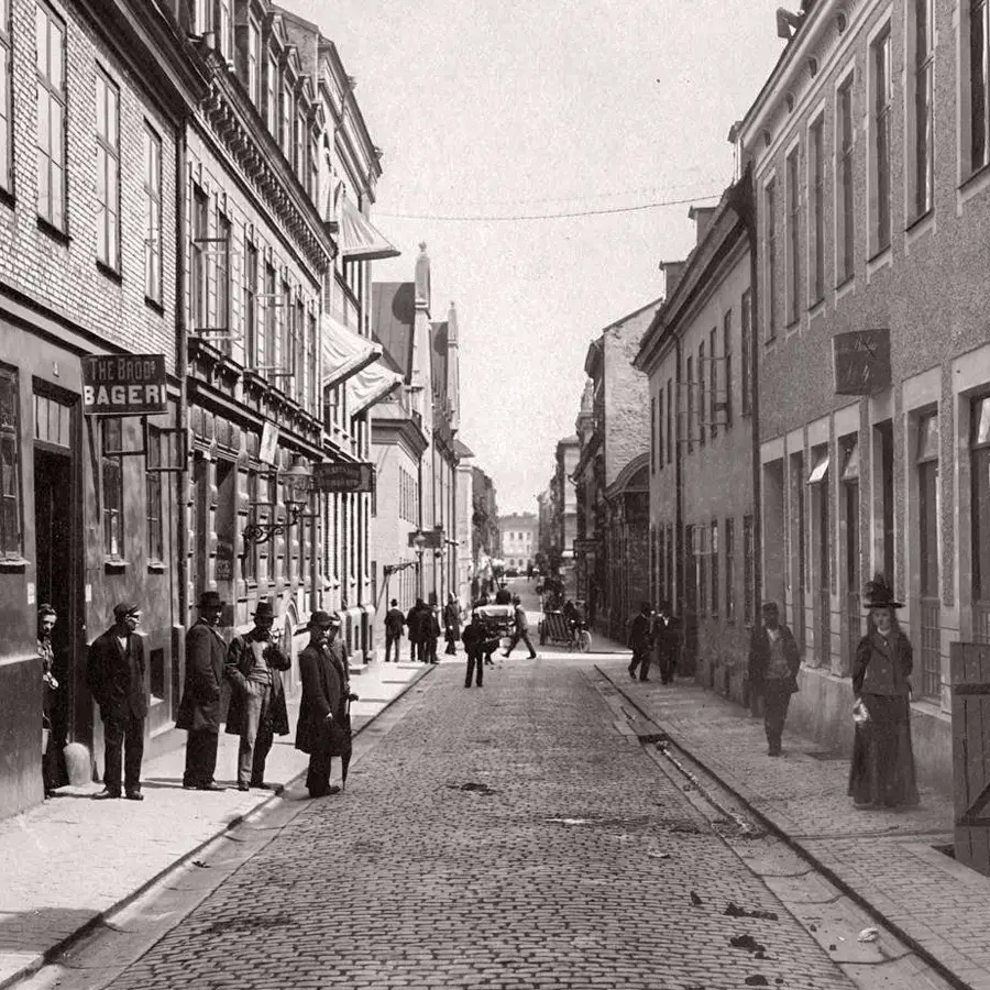 Svartvit historisk bild av Vallgatan i Göteborg med människor och husfasader.